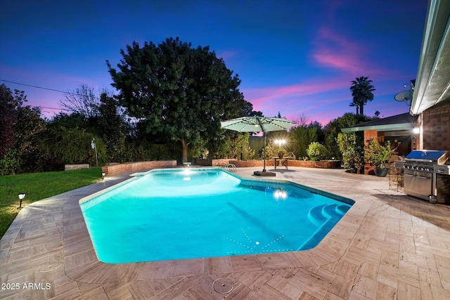 pool at dusk featuring pool water feature, grilling area, and a patio area