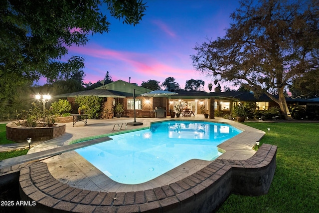 pool at dusk featuring a yard, a diving board, and a patio