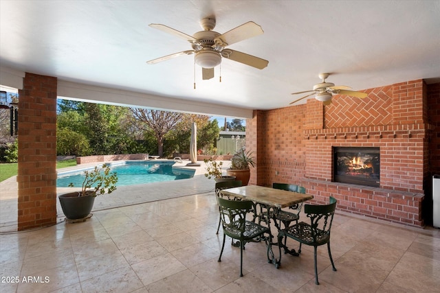 view of swimming pool featuring an outdoor brick fireplace, a patio, and ceiling fan