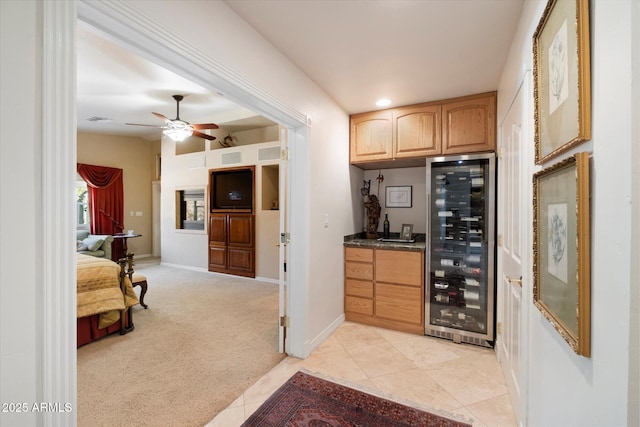 bar with light carpet, beverage cooler, and ceiling fan