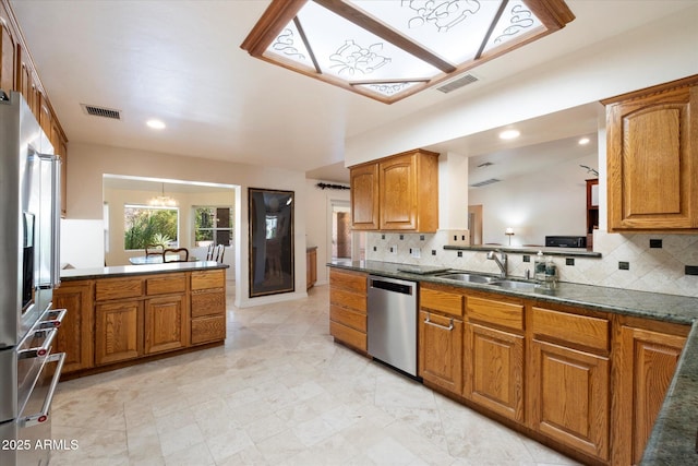 kitchen with sink, backsplash, a notable chandelier, kitchen peninsula, and stainless steel appliances