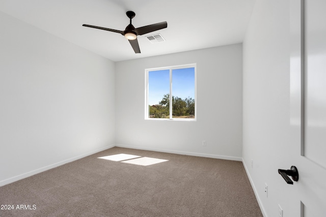 carpeted spare room featuring baseboards, visible vents, and ceiling fan