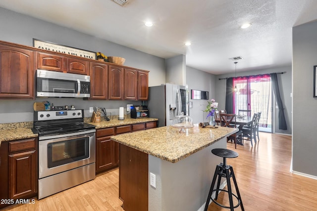 6328 W Fawn Dr, Laveen, AZ 85339 - kitchen with a center island, stainless steel appliances, light wood-type flooring, visible vents, and pendant lighting