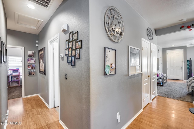 6328 W Fawn Dr, Laveen, AZ 85339 - hall featuring visible vents, a textured wall, light wood-style floors, attic access, and baseboards