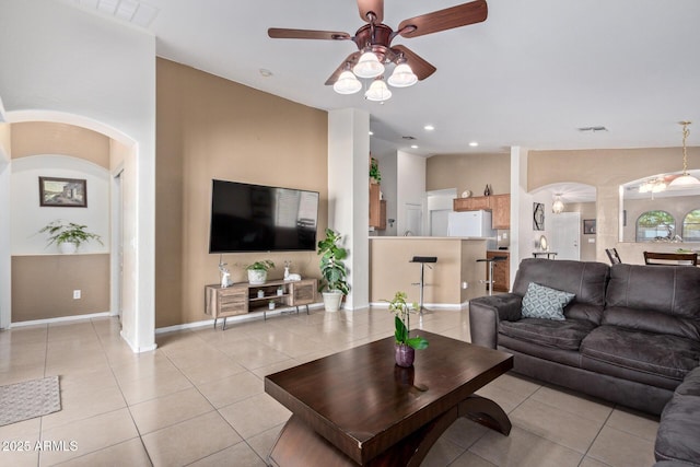 living area featuring arched walkways, lofted ceiling, visible vents, a ceiling fan, and light tile patterned flooring