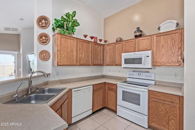 kitchen with brown cabinets, white appliances, light countertops, and a sink