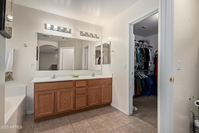 full bathroom featuring double vanity, a sink, a bath, and tile patterned floors