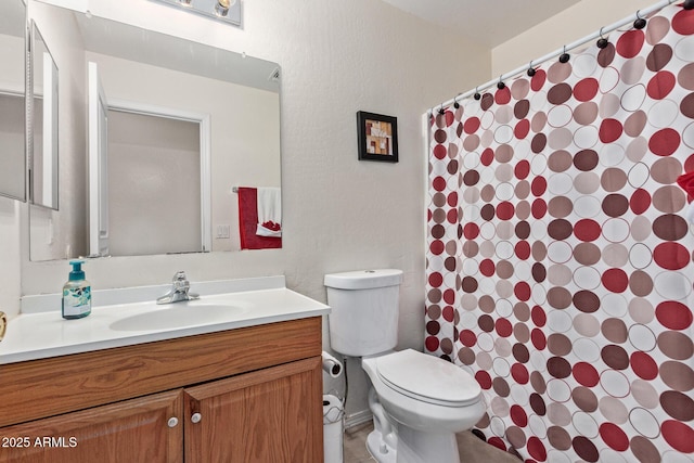 bathroom featuring a textured wall, vanity, and toilet