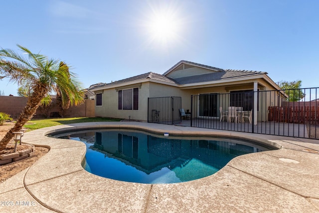 rear view of property featuring a fenced in pool, a patio area, fence, and stucco siding