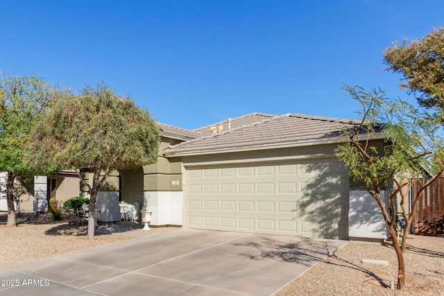 view of front facade featuring a garage, fence, a tile roof, driveway, and stucco siding