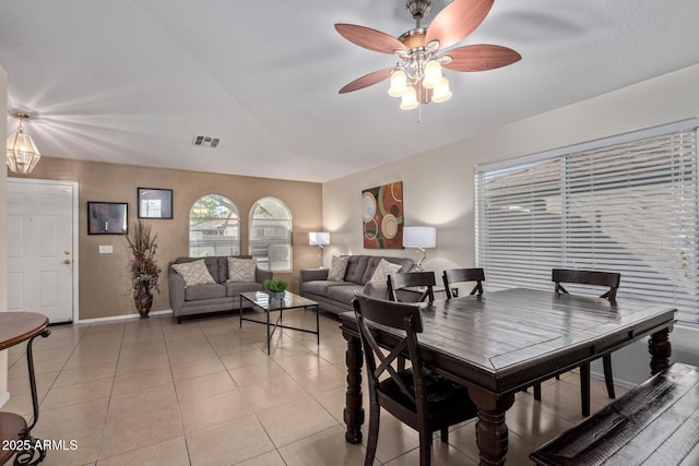 dining room with lofted ceiling, light tile patterned flooring, a ceiling fan, visible vents, and baseboards