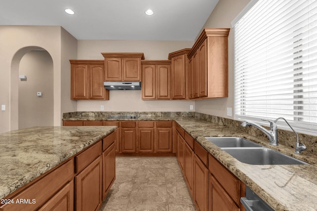 kitchen with dishwasher, light stone counters, black electric cooktop, and sink