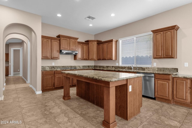 kitchen featuring light stone countertops, stainless steel dishwasher, a kitchen island, and black stovetop