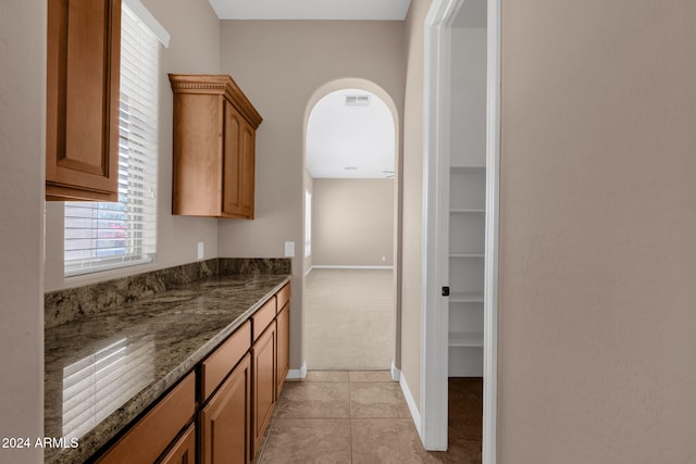 kitchen featuring light carpet and dark stone counters