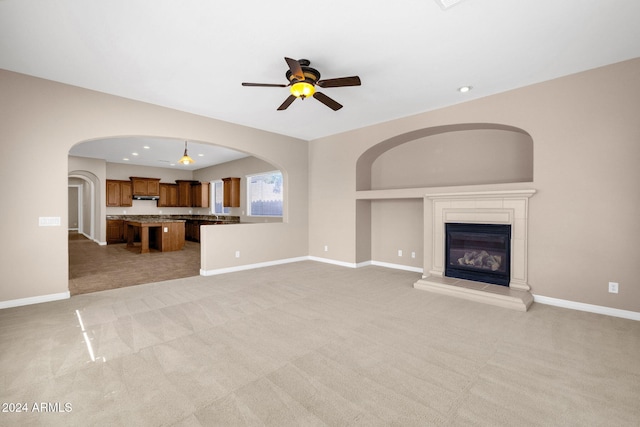 unfurnished living room featuring ceiling fan and light colored carpet