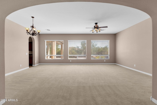 empty room with light carpet, ceiling fan with notable chandelier, and a wealth of natural light