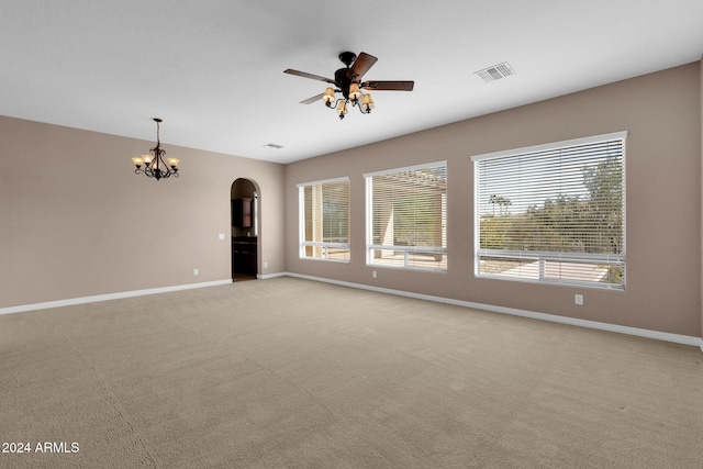 empty room featuring ceiling fan with notable chandelier and light carpet