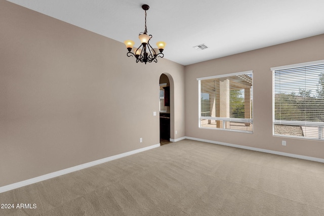 carpeted empty room with a notable chandelier