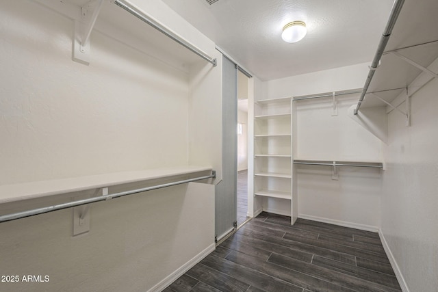 walk in closet with dark wood-style flooring
