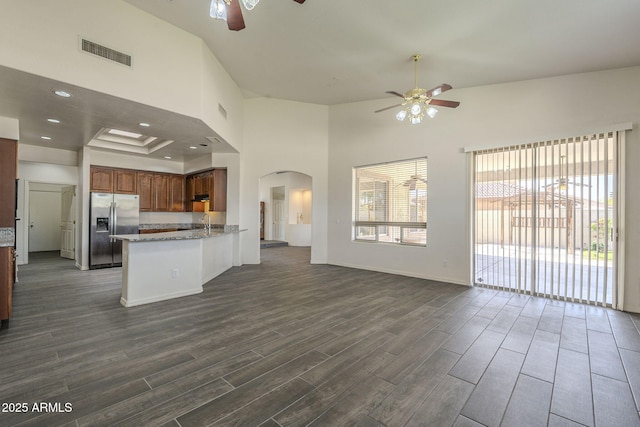 kitchen with open floor plan, a ceiling fan, stainless steel fridge with ice dispenser, and visible vents
