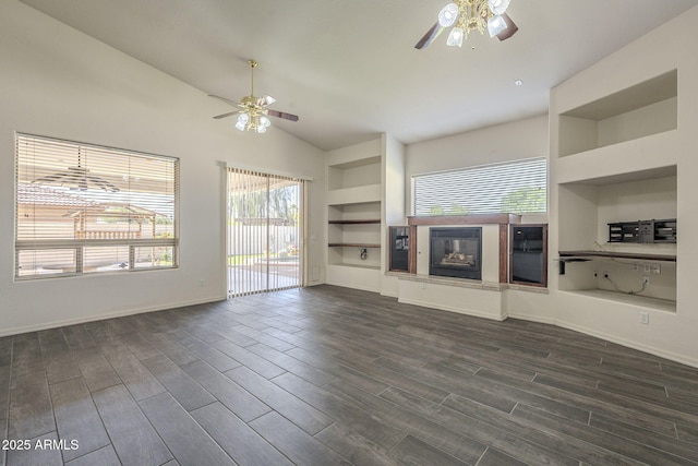 unfurnished living room with built in features, dark wood finished floors, a glass covered fireplace, and ceiling fan