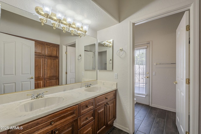 full bathroom with toilet, wood finished floors, double vanity, and a sink