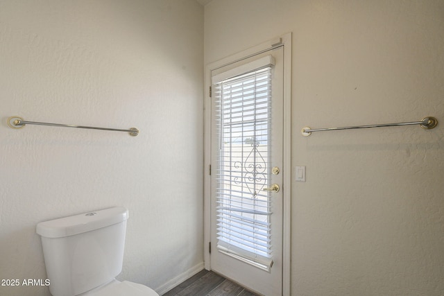 bathroom featuring toilet, a healthy amount of sunlight, and wood finished floors