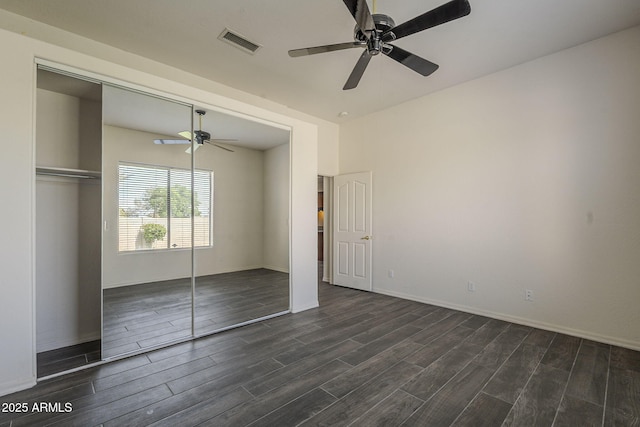 unfurnished bedroom featuring a closet, dark wood-style flooring, visible vents, baseboards, and a ceiling fan