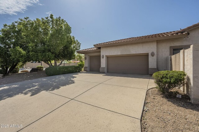 view of side of home featuring a tile roof, driveway, stucco siding, and an attached garage