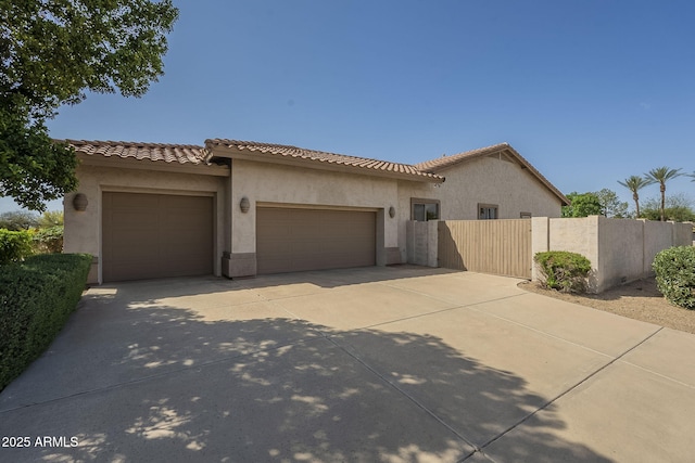 mediterranean / spanish house with stucco siding, a tile roof, a garage, and driveway