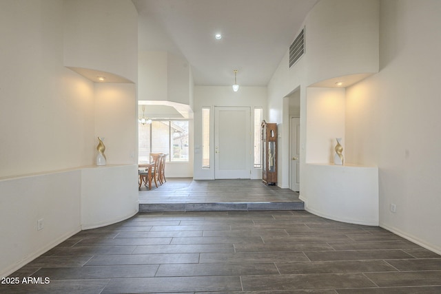 entrance foyer with visible vents, a notable chandelier, a towering ceiling, and wood finish floors