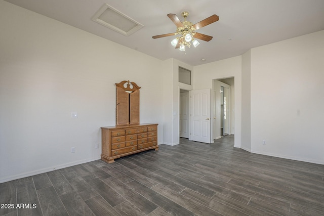 unfurnished bedroom featuring a ceiling fan, dark wood-style floors, attic access, and baseboards