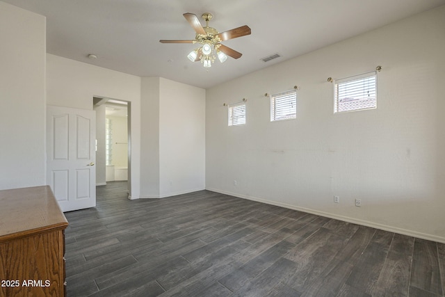 empty room featuring baseboards, dark wood-style flooring, ceiling fan, and visible vents