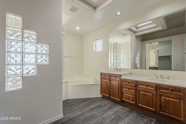 bathroom featuring double vanity, wood finished floors, a sink, and a garden tub