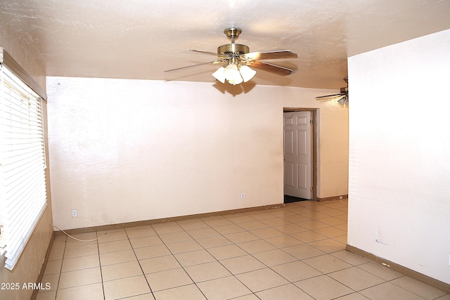 unfurnished room with ceiling fan, light tile patterned floors, a textured ceiling, and baseboards