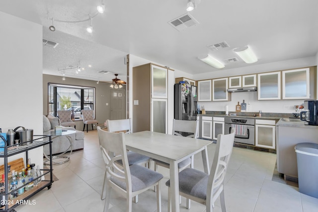 tiled dining area with ceiling fan and a textured ceiling