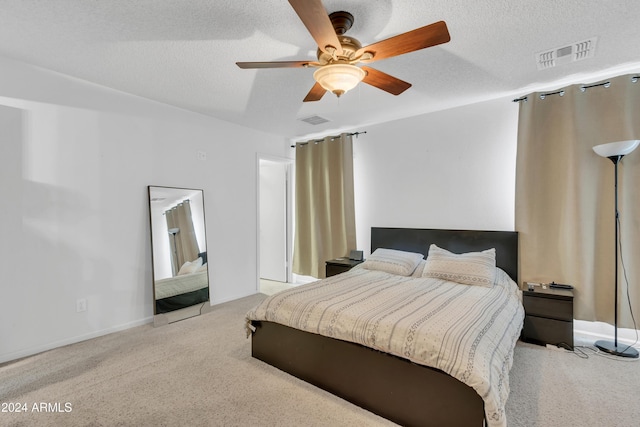 bedroom featuring ceiling fan, a textured ceiling, and light carpet