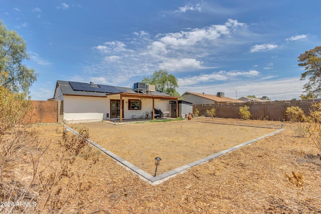 rear view of house with cooling unit and solar panels