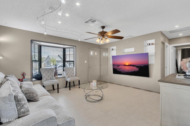 living room with ceiling fan and a textured ceiling