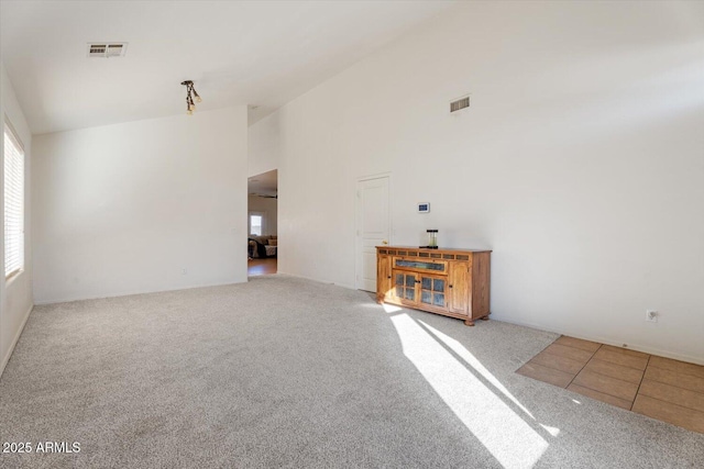 unfurnished living room with carpet and high vaulted ceiling