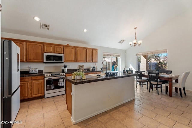 kitchen featuring stainless steel electric range oven, a center island with sink, decorative light fixtures, a notable chandelier, and refrigerator