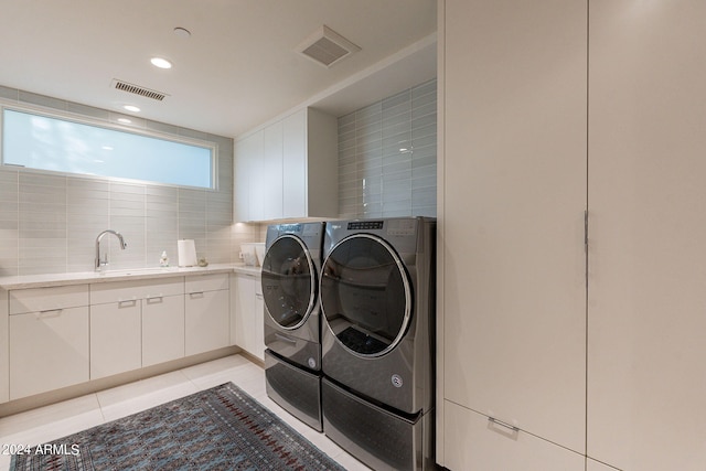 clothes washing area featuring light tile patterned flooring, washer and clothes dryer, cabinets, and sink