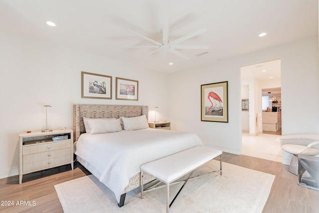 bedroom with connected bathroom, light hardwood / wood-style flooring, and ceiling fan