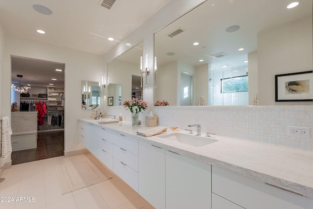 bathroom with tile patterned flooring, vanity, decorative backsplash, and a shower with door