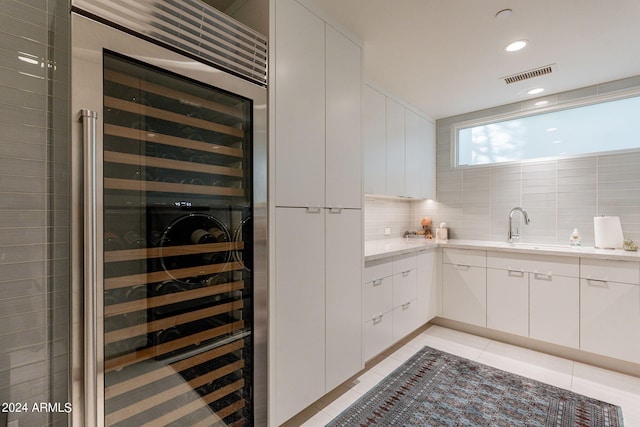 kitchen with white cabinets, sink, backsplash, and wine cooler