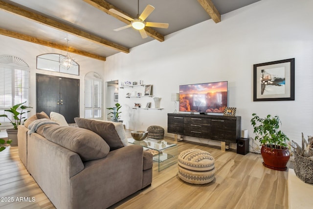 living room featuring ceiling fan with notable chandelier, beam ceiling, and light hardwood / wood-style floors