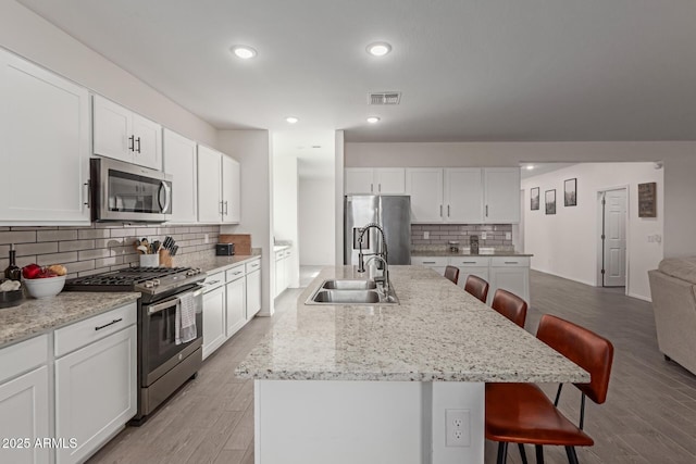 47469 W Cansados Rd, Maricopa, AZ 85139 - kitchen featuring appliances with stainless steel finishes, a breakfast bar, decorative backsplash, an island with sink, and recessed lighting