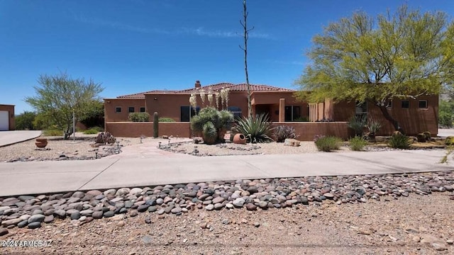 view of front of property with a tile roof, stucco siding, and a chimney