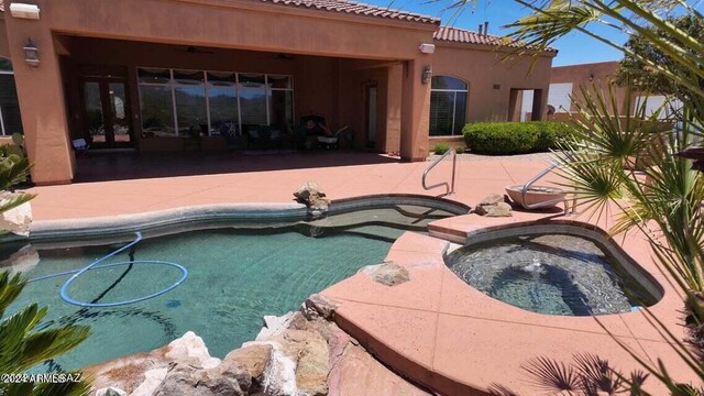 outdoor pool with an in ground hot tub and a patio area