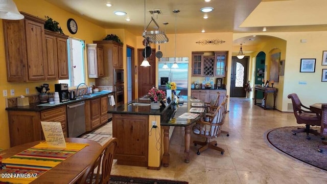 kitchen featuring a sink, a kitchen breakfast bar, arched walkways, brown cabinetry, and built in appliances